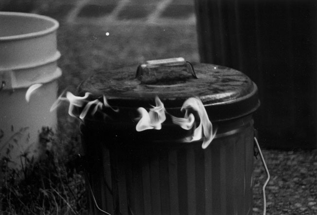 A closed, but fiery trashcan being used to cool Raku pottery