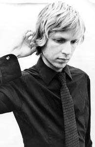 Photo of Beck looking down and scratching the back of his head.