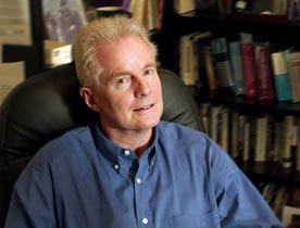 A photograph of David Kirby smiling faintly while seated in an office chair turned slightly away (This is a link to his website).