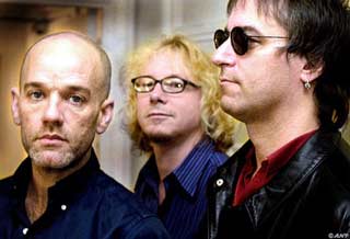 Photograph of the R.E.M. band members standing beside each other looking in different directions.