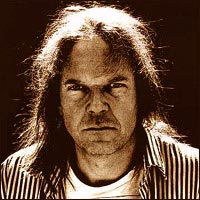 A sepia image of Neil Young in a striped shirt staring ahead meanly with light from behind him reflecting off of his hair.